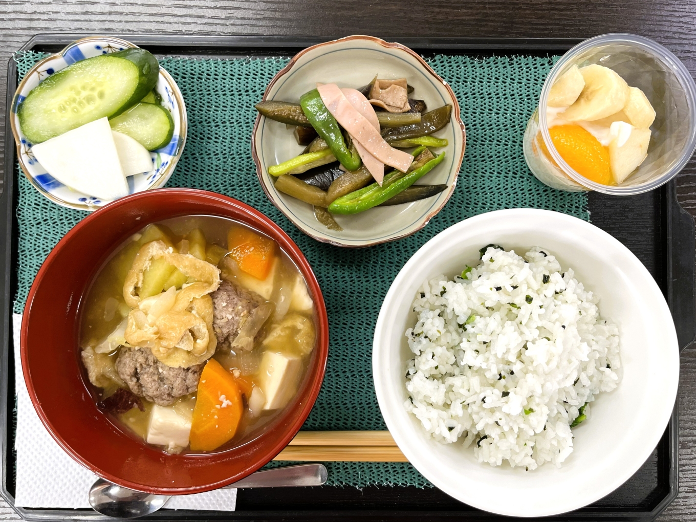 11月15日のメニューの写真です。トレーの上に、わかめ入り菜飯、サツマイモと肉団子のみそ汁、 もやい畑のナスとピーマンの炒め物、きゅうりとかぶの浅漬け、フルーツヨーグルト、が載せられています。